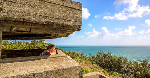 Woman standing by retaining wall against sea