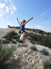 Full length of young woman jumping on sand