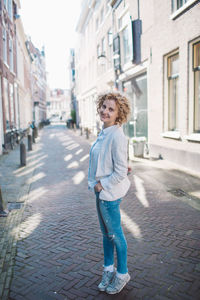 Portrait of smiling woman standing on footpath amidst buildings