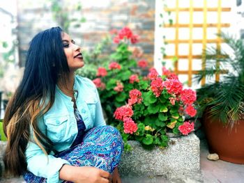 Young woman looking down while standing on flower pot