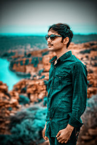 Young man wearing sunglasses standing on beach