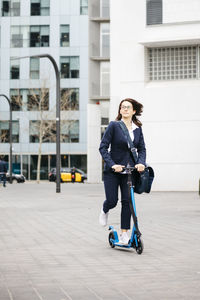 Active businesswoman riding scooter in the city