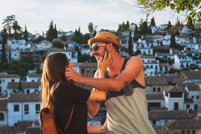 Happy friends greeting against houses in town