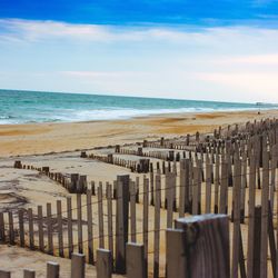 Wooden fence at beach against sky