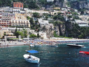 High angle view of sailboats moored on sea by buildings in city