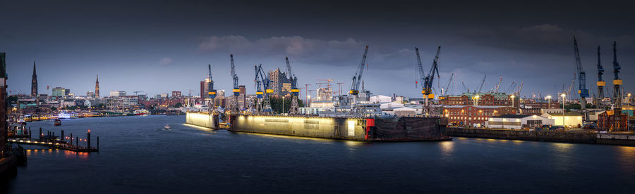 Panoramic view of illuminated commercial dock against sky