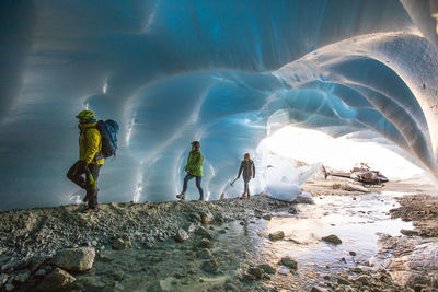 Adventure guide brings two female clients into a glacial cave.