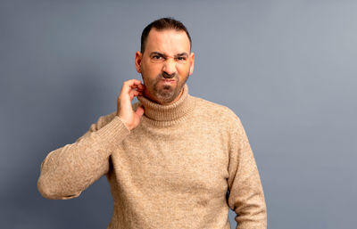 Portrait of young man standing against blue background