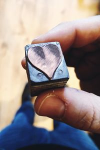 Close-up of hand holding metal cube with heart shape