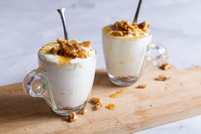 Cups of yogurt with honey and nuts on white background