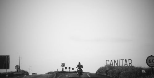 Rear view of man with text against sky