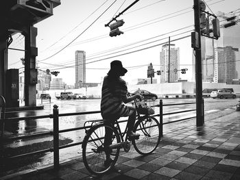 Man riding bicycle on bridge in city