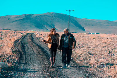 Full length of friends standing on mountain against sky