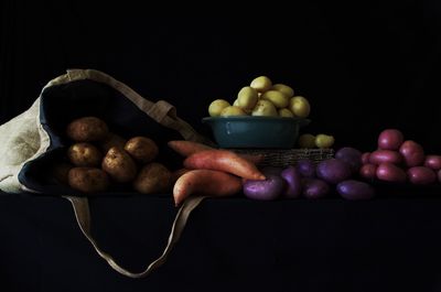 Close-up of hand holding grapes over black background