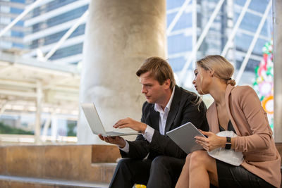 Friends looking away while sitting on mobile phone