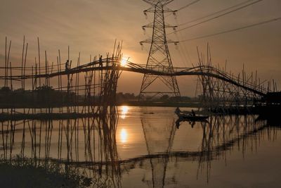 Silhouette of electricity pylon against sky during sunset