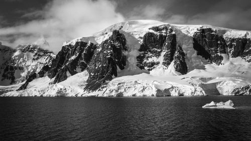 Black and white photo of glacier against snowcapped mountain in antarctica