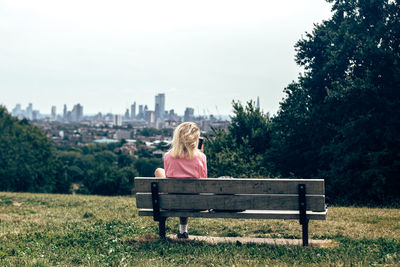 Rear view of woman sitting on bench in park