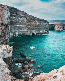 Rock formations on shore against sky