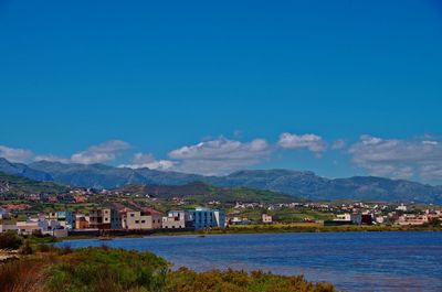 Buildings by sea against blue sky