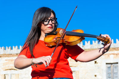 Young woman wearing sunglasses standing against the sky