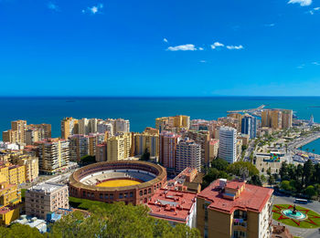 High angle view of buildings and sea against blue sky