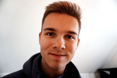 Close-up portrait of smiling young man against wall
