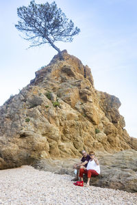 Retired couple sitting on a rocky area near the sea