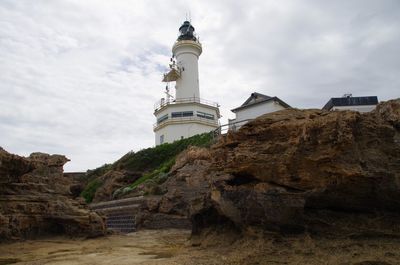 Low angle view of lighthouse by buildings against sky