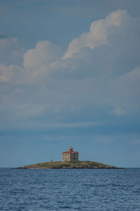 Lighthouse by sea against sky