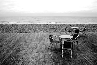 Chairs and table on beach against sky