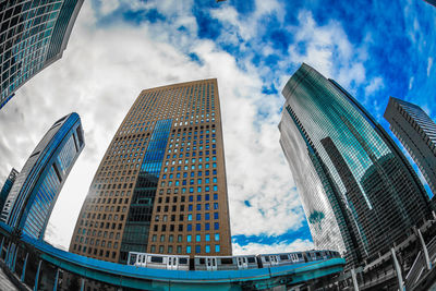 Low angle view of modern buildings against cloudy sky