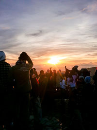 Group of people photographing at sunset