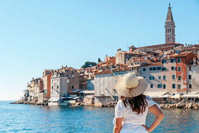 Young woman from behind. picturesque old town by sea in background.