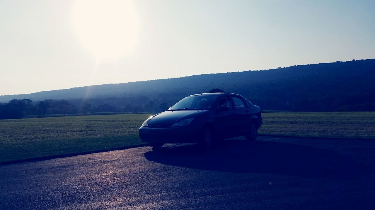 transportation, clear sky, mountain, mode of transport, sun, sunlight, landscape, one person, copy space, car, land vehicle, tranquil scene, road, tranquility, lens flare, mountain range, scenics, nature, sky, beauty in nature