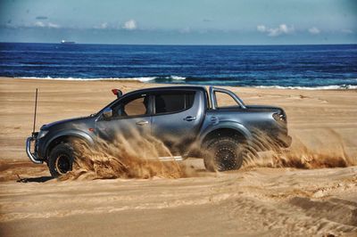 Car on beach by sea against sky