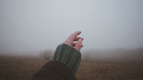 Midsection of person on field against sky during foggy weather