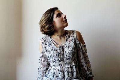 Young woman standing against white wall