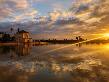 Scenic view of lake by buildings against sky during sunset