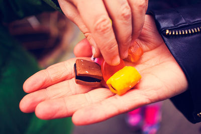 Cropped hand of man offering sweet food to friend