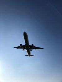 Low angle view of airplane flying against clear blue sky