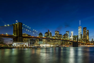 Illuminated bridge over river against sky in city at night