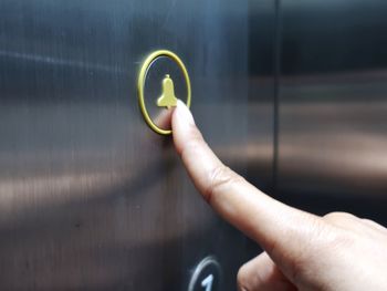 Cropped image of hand pressing button in elevator