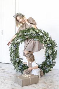 A young woman with blonde hair and a little daughter with a christmas wreath. new year's concept