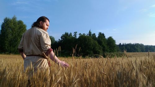 Young woman in field against sky