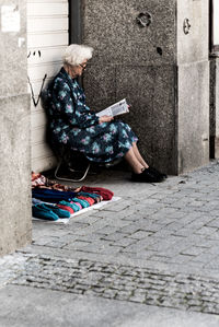 Low section of woman sitting on footpath