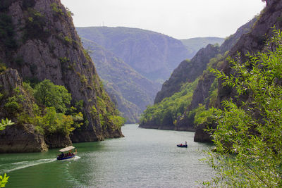 Scenic view of river amidst trees and mountains against sky