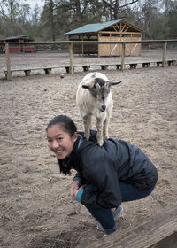Girl playing with kid goat at farm