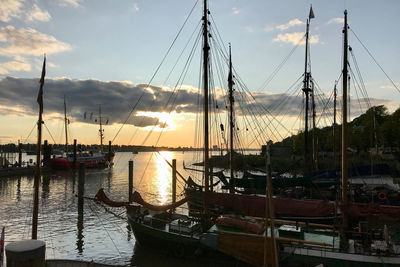 Sailboats moored in marina at sunset