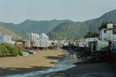 Buildings by mountains against clear sky